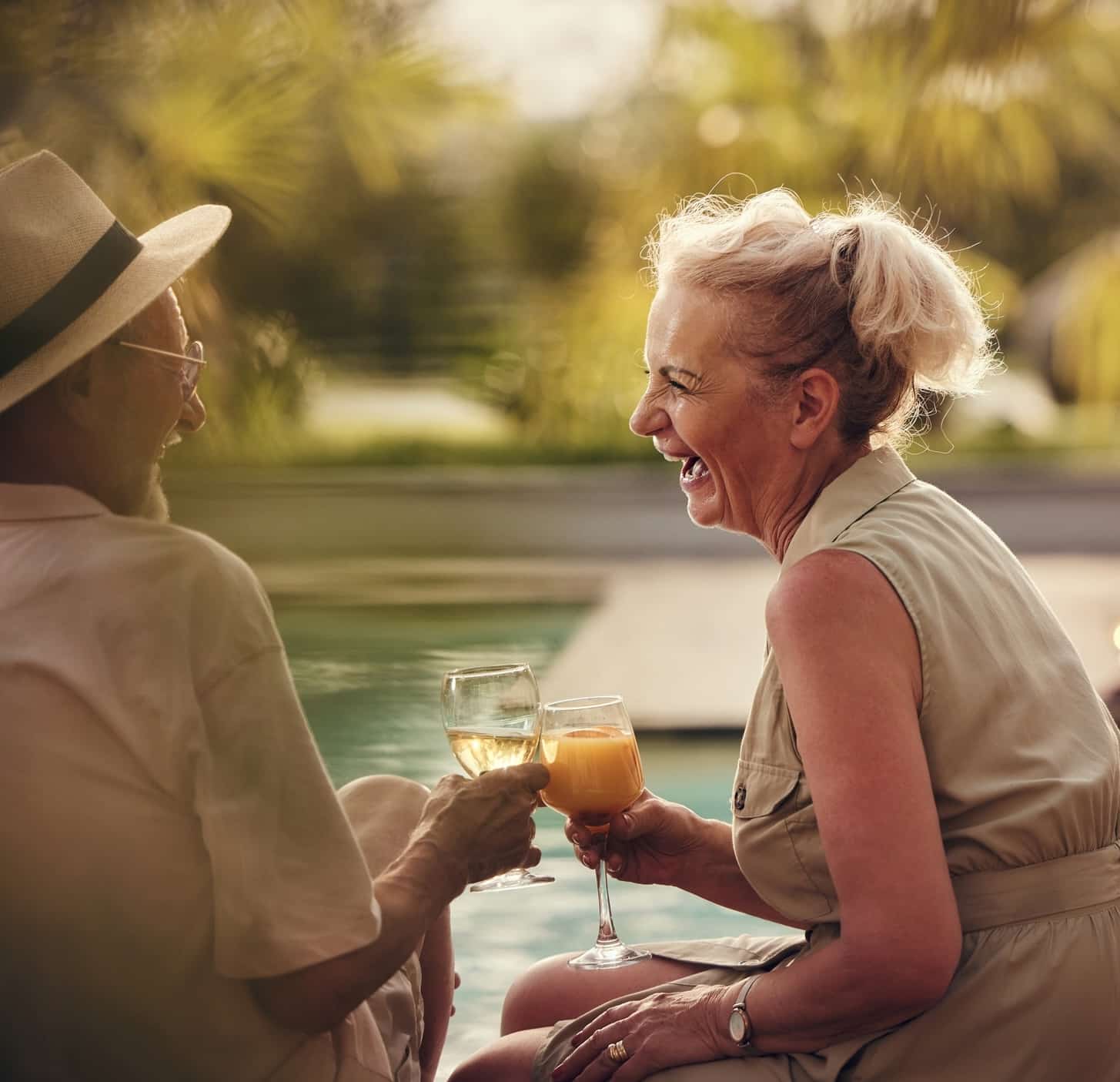 Carefree senior couple having fun while toasting by the pool during social gathering in the backyard.